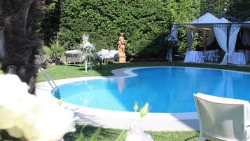A pool with a statue, a gazebo, and outdoor seating.