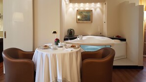 Una habitación con una mesa de comedor dispuesta para dos personas, una bañera y un cuadro en la pared.