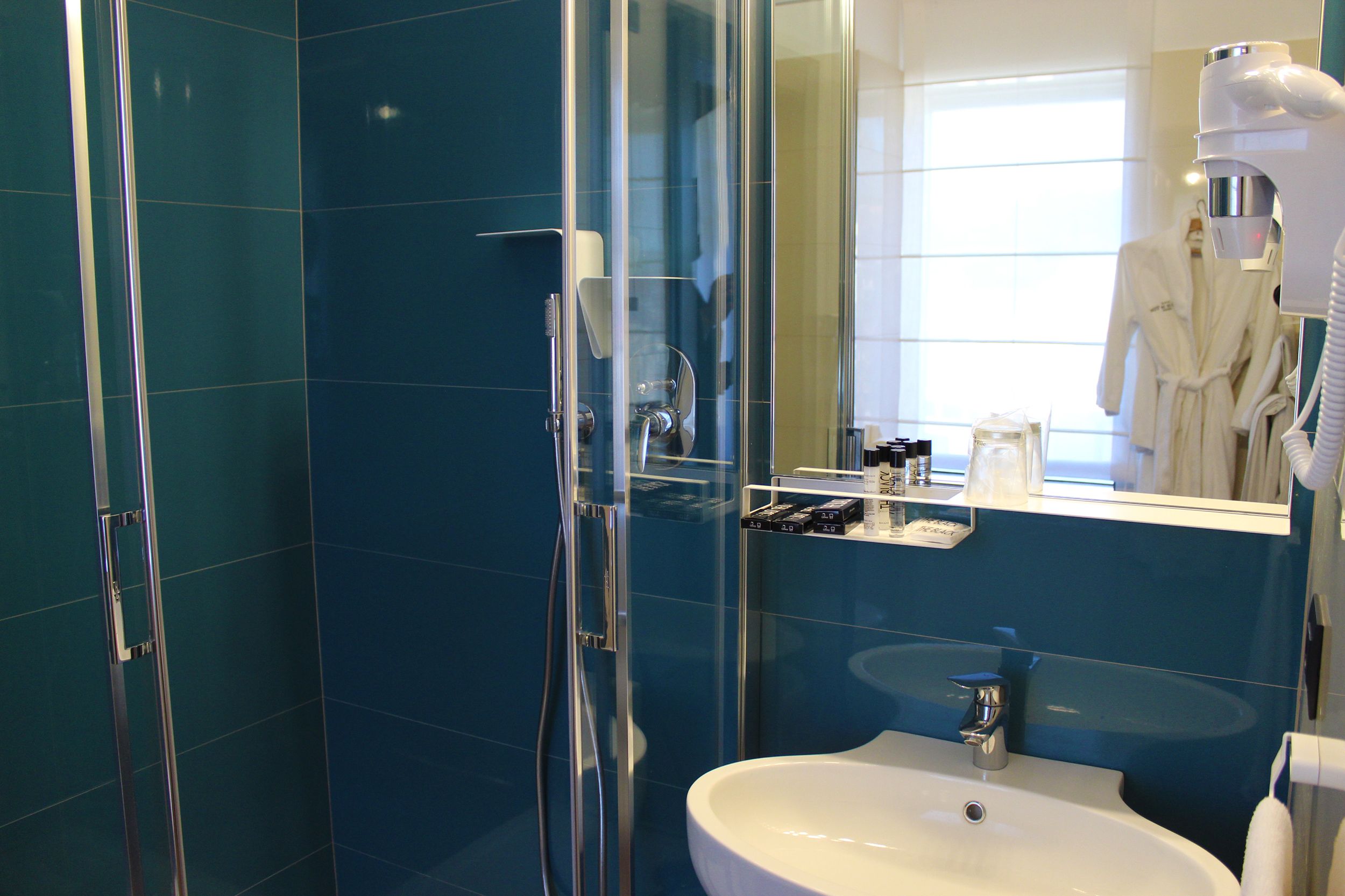 Ein modernes Badezimmer mit Duschkabine aus Glas, einem weißen Waschbecken und einem Waschtisch mit Toilettenartikeln.