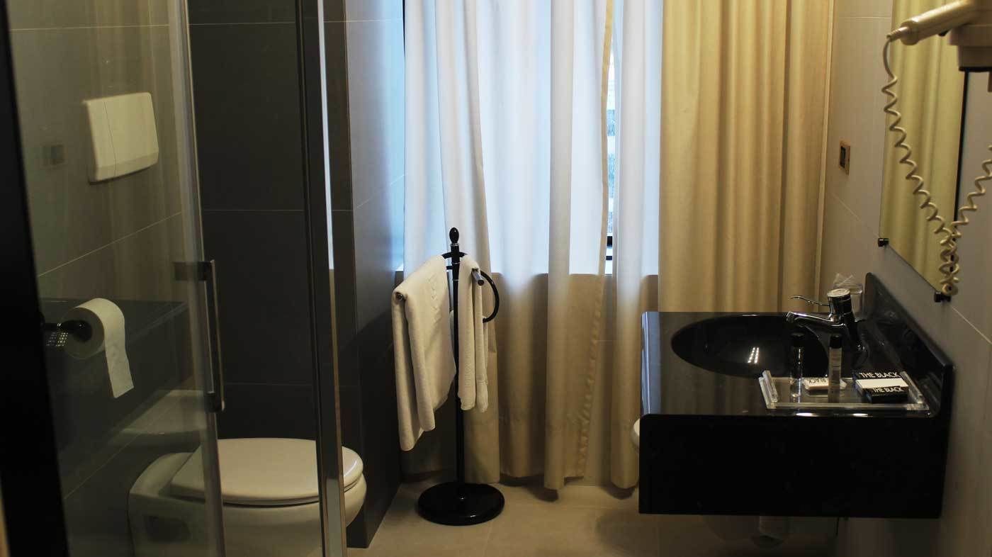 Un baño con cabina de ducha de vidrio, inodoro, lavabo con espejo y toallero.