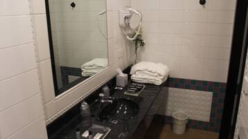 A bathroom with a black sink, a mirror, a towel rack, and a trash bin.