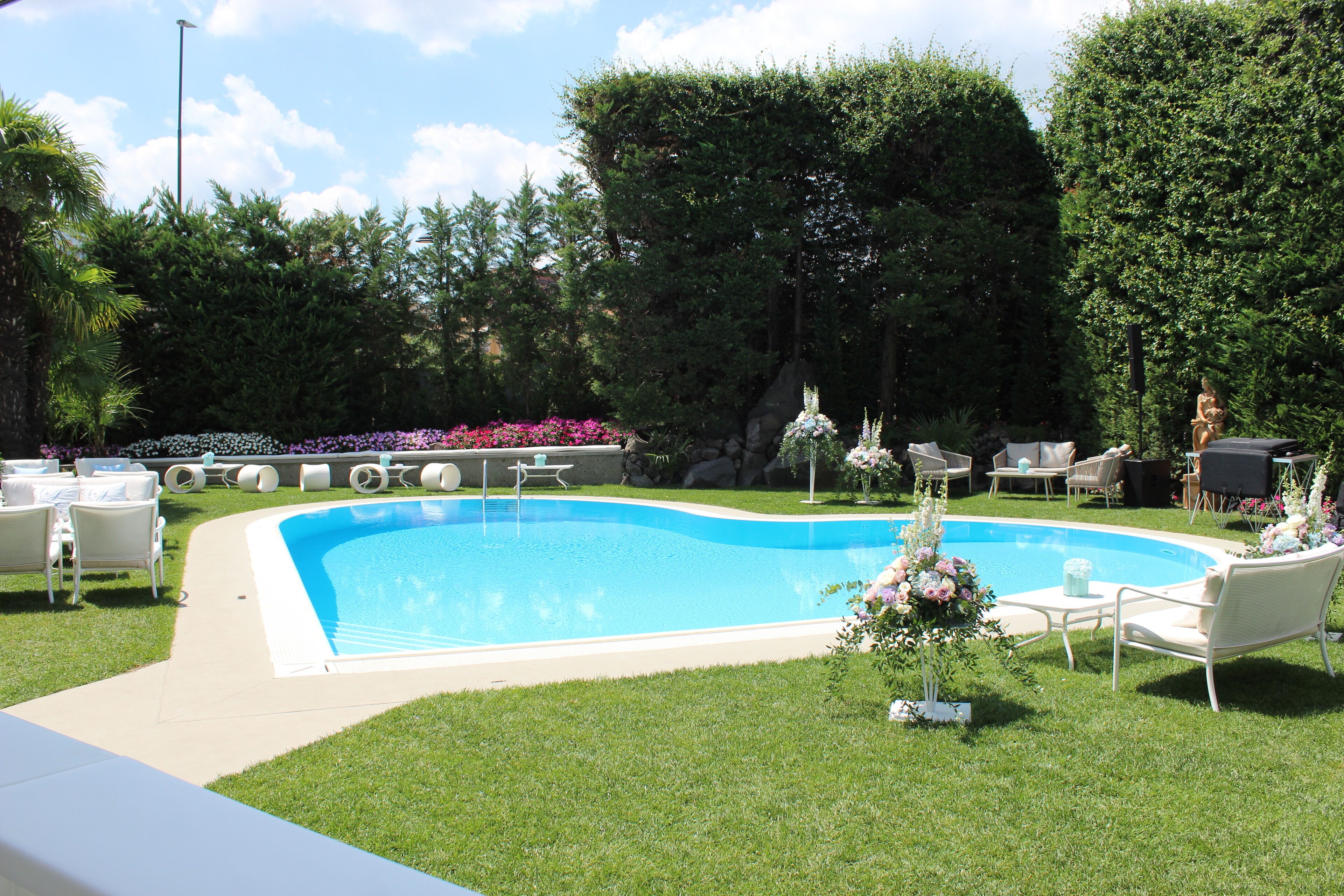 En swimmingpool med en omgivande uteplats, inklusive utemöbler och en blomsterarrangemang.