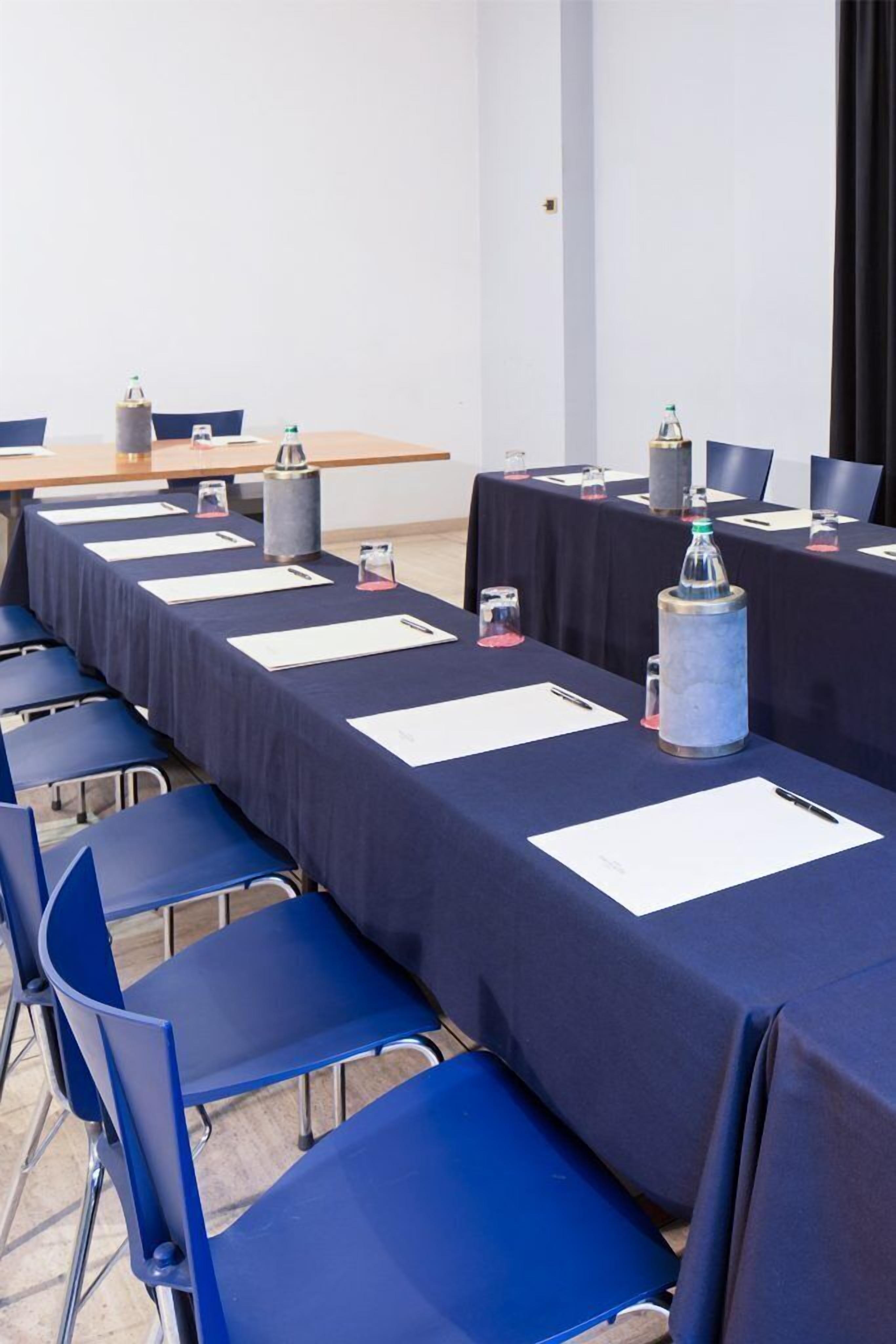 A conference room with long tables, blue chairs, and water bottles.