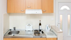 A modern kitchen with wooden cabinets, a stainless steel sink, a built-in oven, a kettle, and a wine bottle. - Guest House Luce (Dubrovnik)