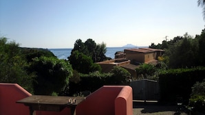 Una terraza con vista al mar y una montaña al fondo.