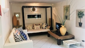 Una sala de estar con un sofá, una mesa de centro, un televisor y un jarrón decorativo.