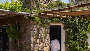 A stone building with a wooden deck and a doorway. - Ikies of Mykonos (Mykonos)