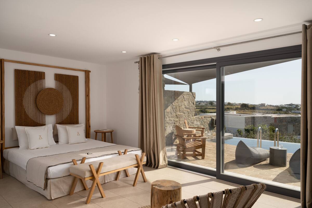 A modern bedroom with a large bed, wooden furniture, and a balcony with a view.