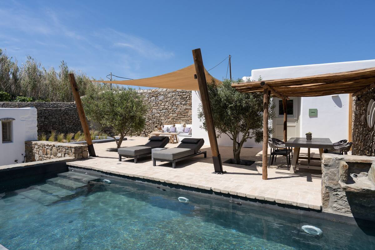 A pool area with lounge chairs, a table, and a pergola.