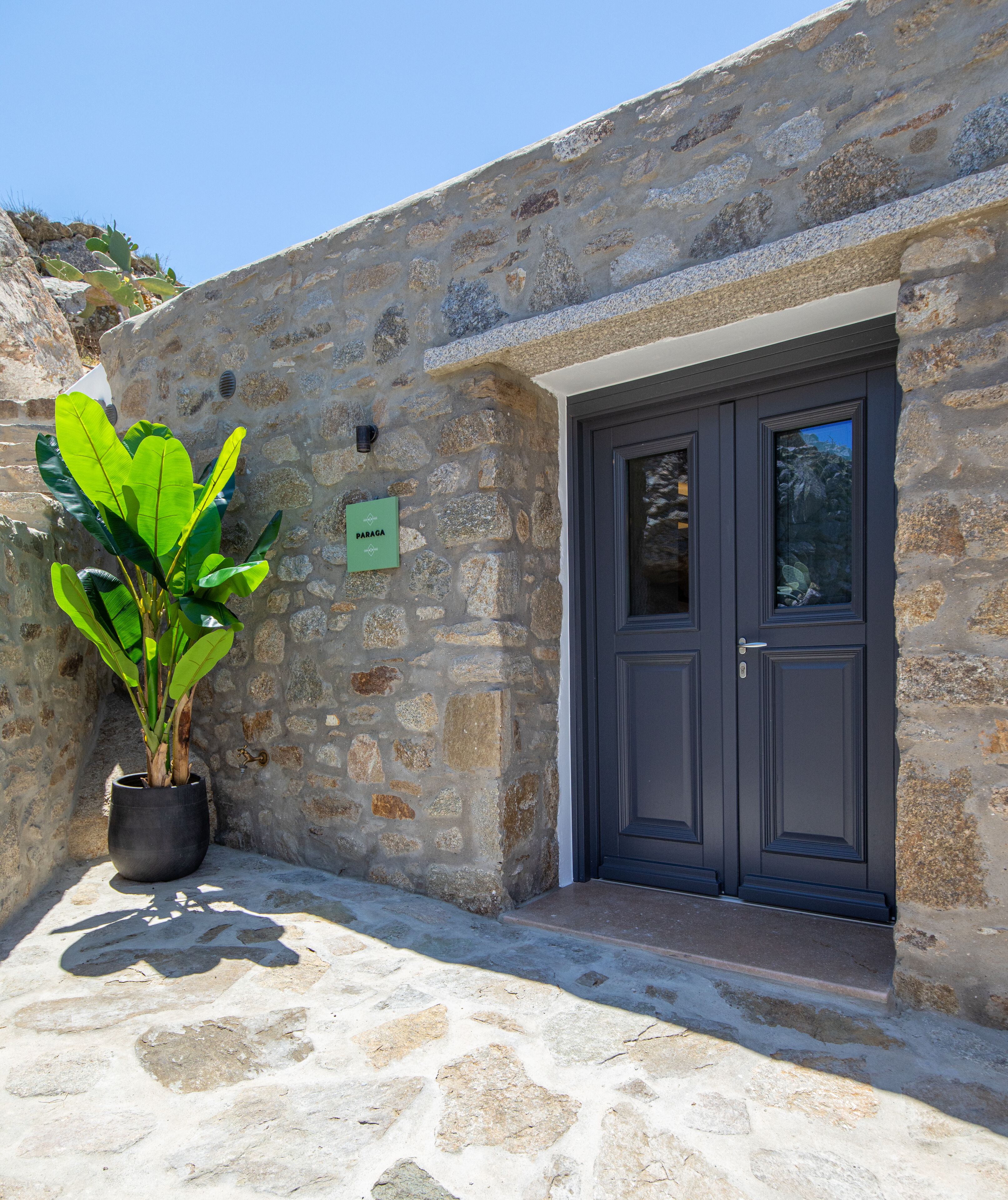 Un edificio in pietra con una porta scura e un cartello verde.