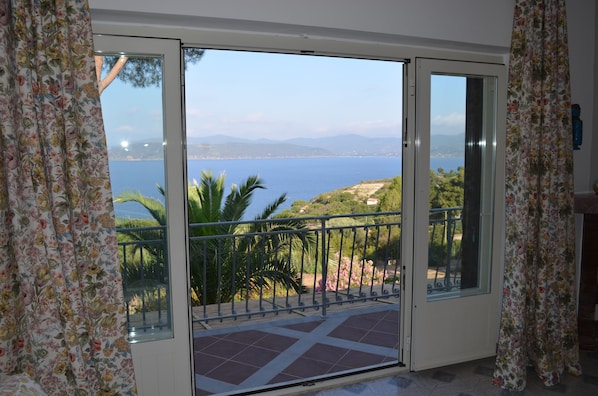 A balcony with a view of the sea and mountains.