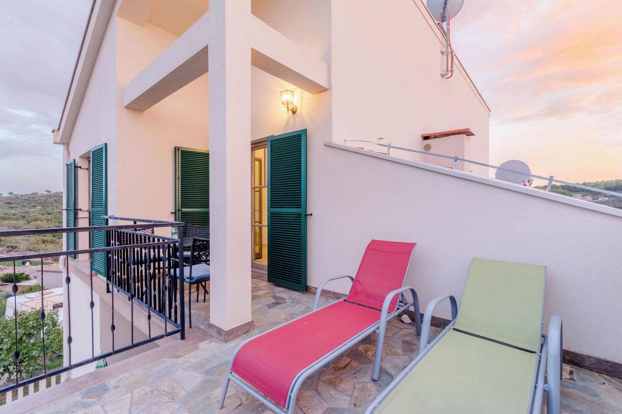 A balcony with two lounge chairs, a table, and chairs, and a view of the landscape.