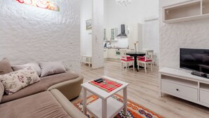 Ein modernes Wohnzimmer mit einer Couch, einem Couchtisch, einem Fernseher und einem Essbereich mit Stühlen und Tisch.
