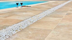 A poolside area with tiled flooring and a pebble border. - Canaryislandshost l My Nest (Nazaret)