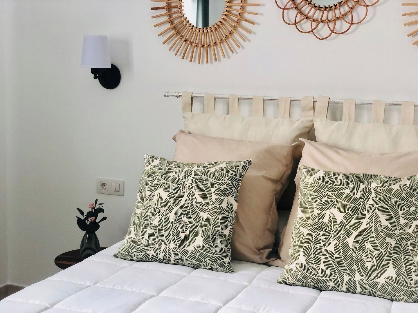 Een bed met witte beddengoed, twee gestreepte kussens en een hoofdbord met een houten frame.