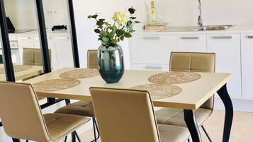 Un comedor moderno con una mesa rectangular, sillas color beige y un florero con flores.