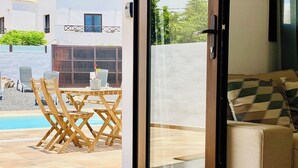 A modern living room with a glass door leading to a pool area. - Canaryislandshost l My Nest (Nazaret)