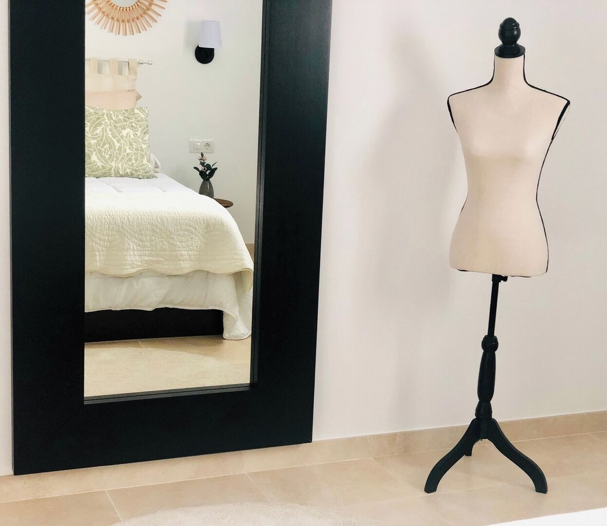 Un dormitorio con cama, mesita de noche, espejo y un maniquí.