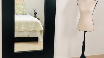 Un dormitorio con cama, mesita de noche, espejo y un maniquí.