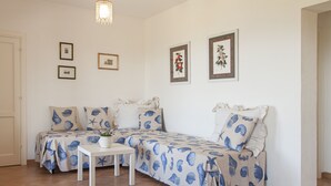 A room with two beds, a small table with a plant, and framed pictures on the wall. - Villetta dello Scrittore (Capoliveri)