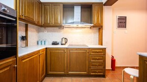 Une cuisine avec des meubles en bois, une hotte de cuisinière en acier inoxydable, une machine à café et un extincteur rouge.