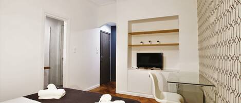 A hotel room with a bed, a TV, a chair, and a desk.