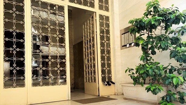 L’entrée d’un hôtel, agrémentée d’une grille décorative, d’un pot de fleurs et d’un sol carrelé.