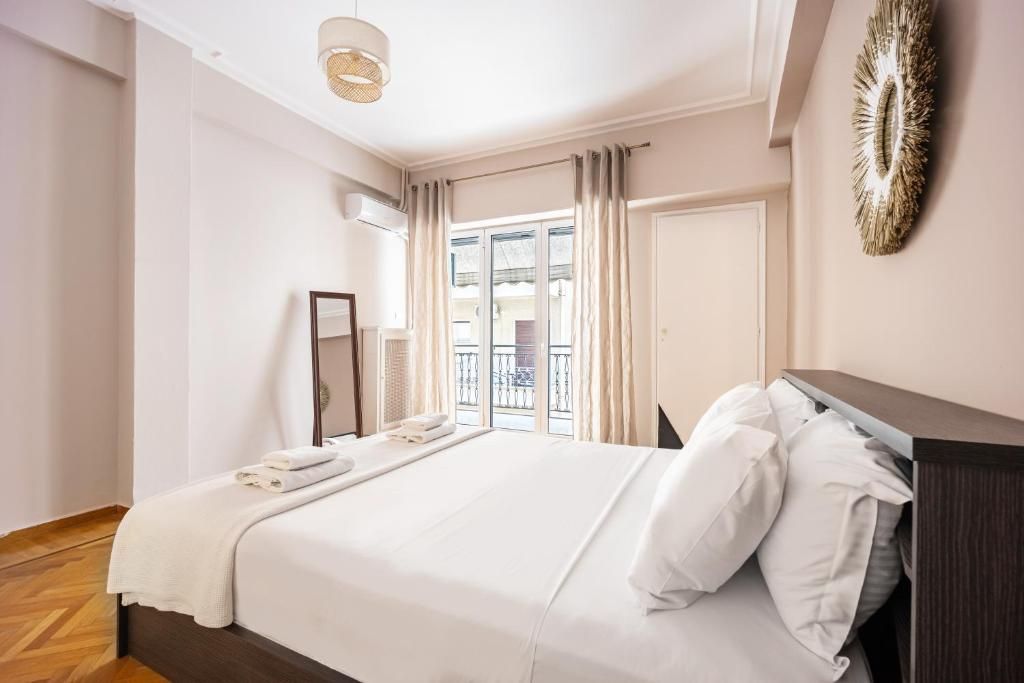A hotel room with a large bed, a bedside table, a mirror, and a view of the outside.