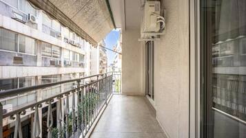 A narrow balcony with a metal railing, a concrete floor, and a view of adjacent buildings.