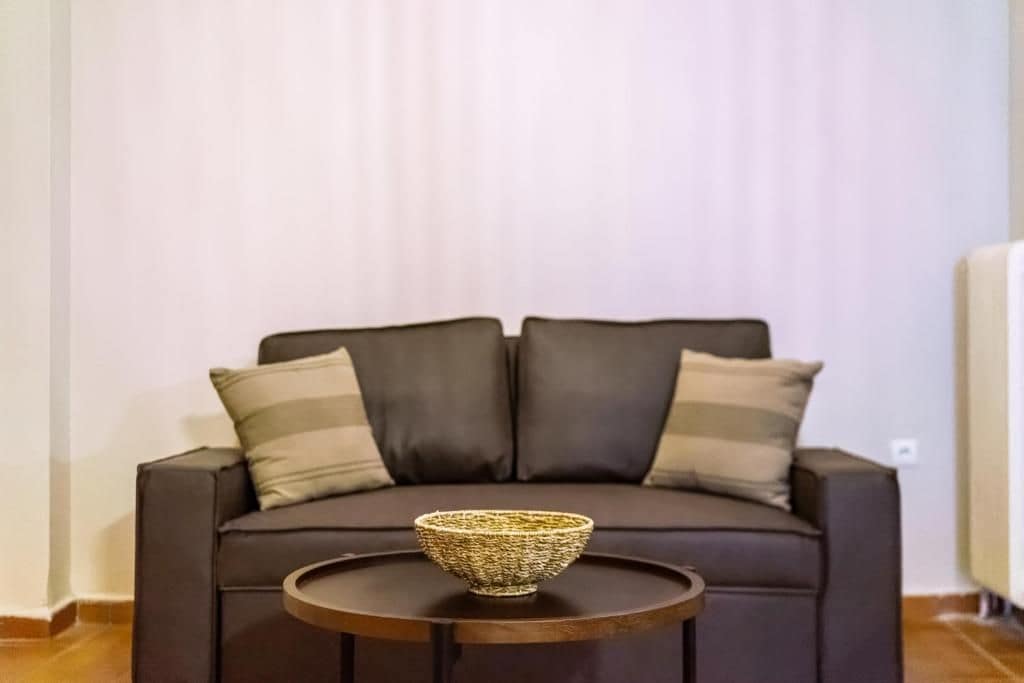 A dark brown sofa with striped cushions and a woven basket on a small round table.