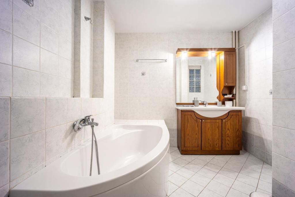 Ein modernes Badezimmer mit einer freistehenden Badewanne, einem Holzkosmetikschrank und einem großen Spiegel.