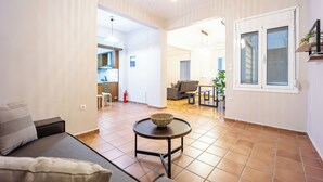 Un salon moderne avec un canapé, une table ronde sur laquelle se trouve un saladier, et une cuisine en arrière-plan.