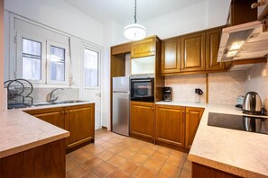 Una cocina con gabinetes de madera, un refrigerador de acero inoxidable, un horno empotrado y una cafetera.