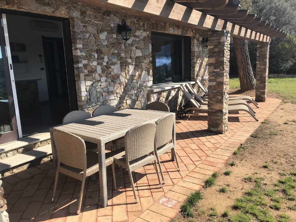 An outdoor patio with a stone wall, wicker furniture, and a pergola.
