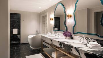 Un baño moderno con una bañera independiente, un tocador con encimera de mármol y un espejo grande con detalles en color turquesa.