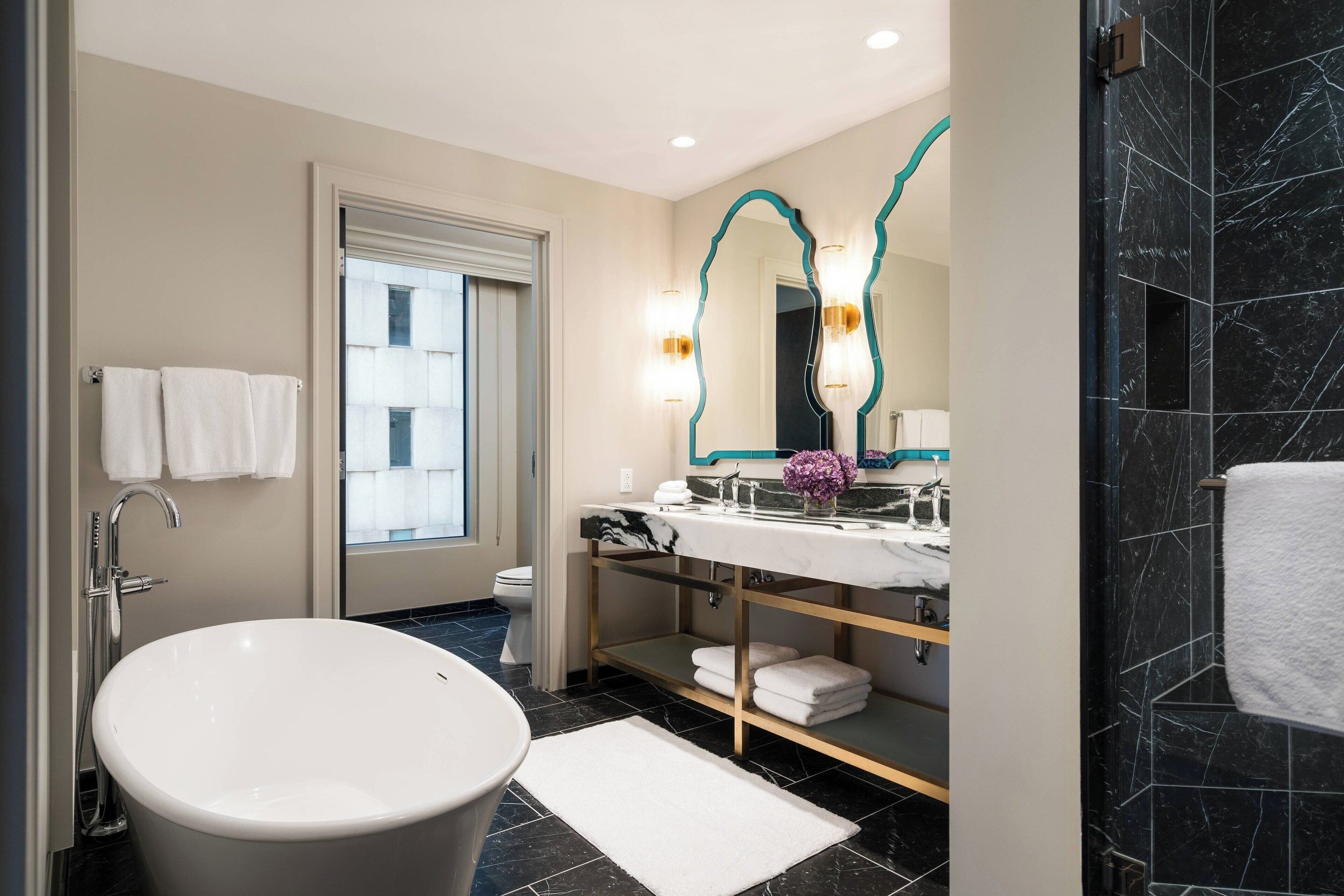 A modern bathroom with a freestanding bathtub, a vanity with a mirror, and a toilet.
