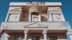 A building with a prominent sign reading "NOMIADS" at the top. - Nomads Hotel Petra (Wadi Musa)