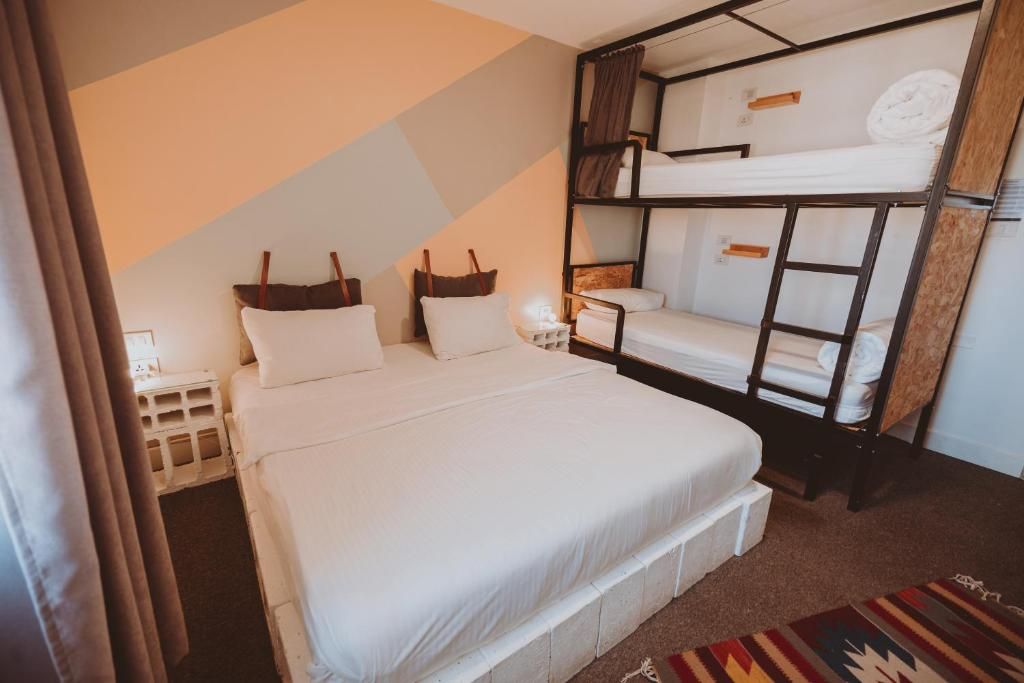 Una habitación de hotel con una cama litera, una cama individual y una mesita de noche.
