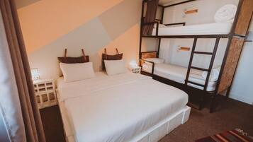 Una habitación de hotel con una cama litera, una cama individual y una mesita de noche.