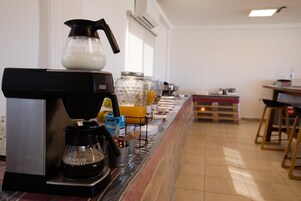 A breakfast bar with a coffee machine, a milk dispenser, and various food containers.