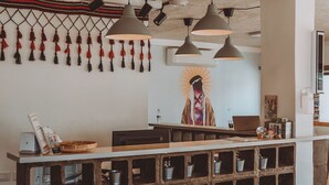 A reception desk with a wooden grid structure, pendant lighting, and a wall-mounted artwork. - Nomads Hotel Petra (Wadi Musa)
