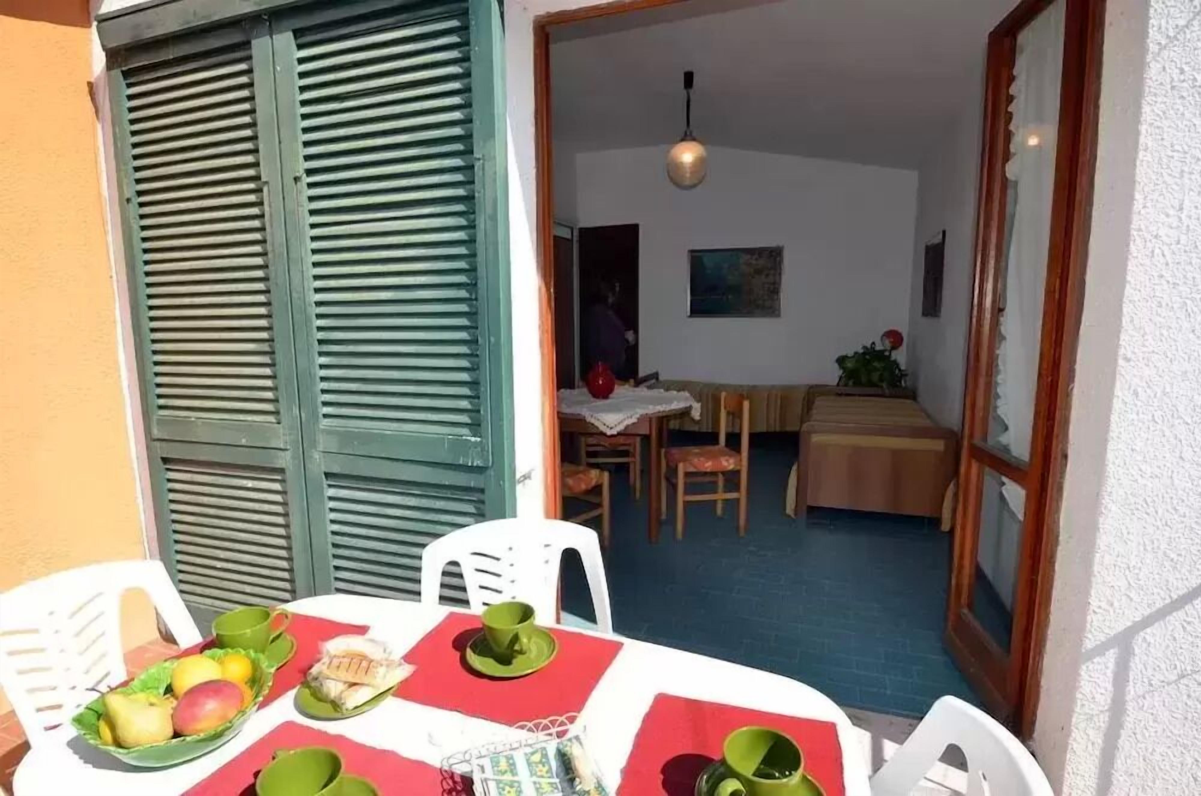 A dining area with a table set for two, a chair, and a small table with a red tablecloth.