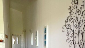 Un pasillo con un sofá estampado, un adorno en la pared y una escalera que lleva a otra habitación.