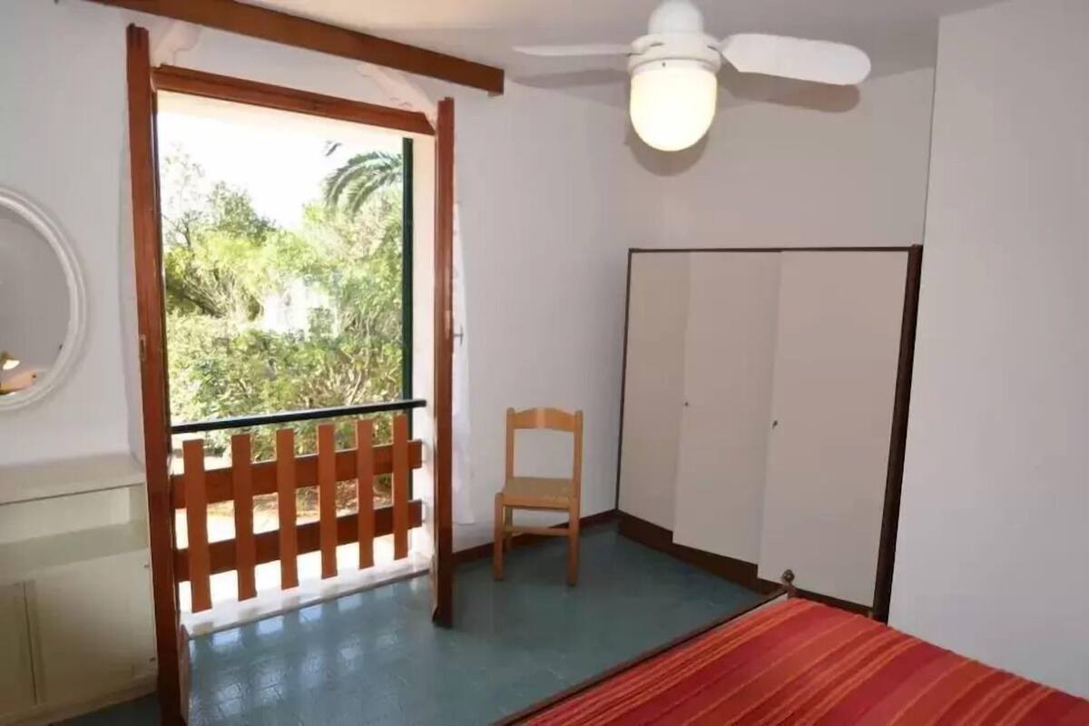 A room with a wooden chair, a wardrobe, and a ceiling fan.