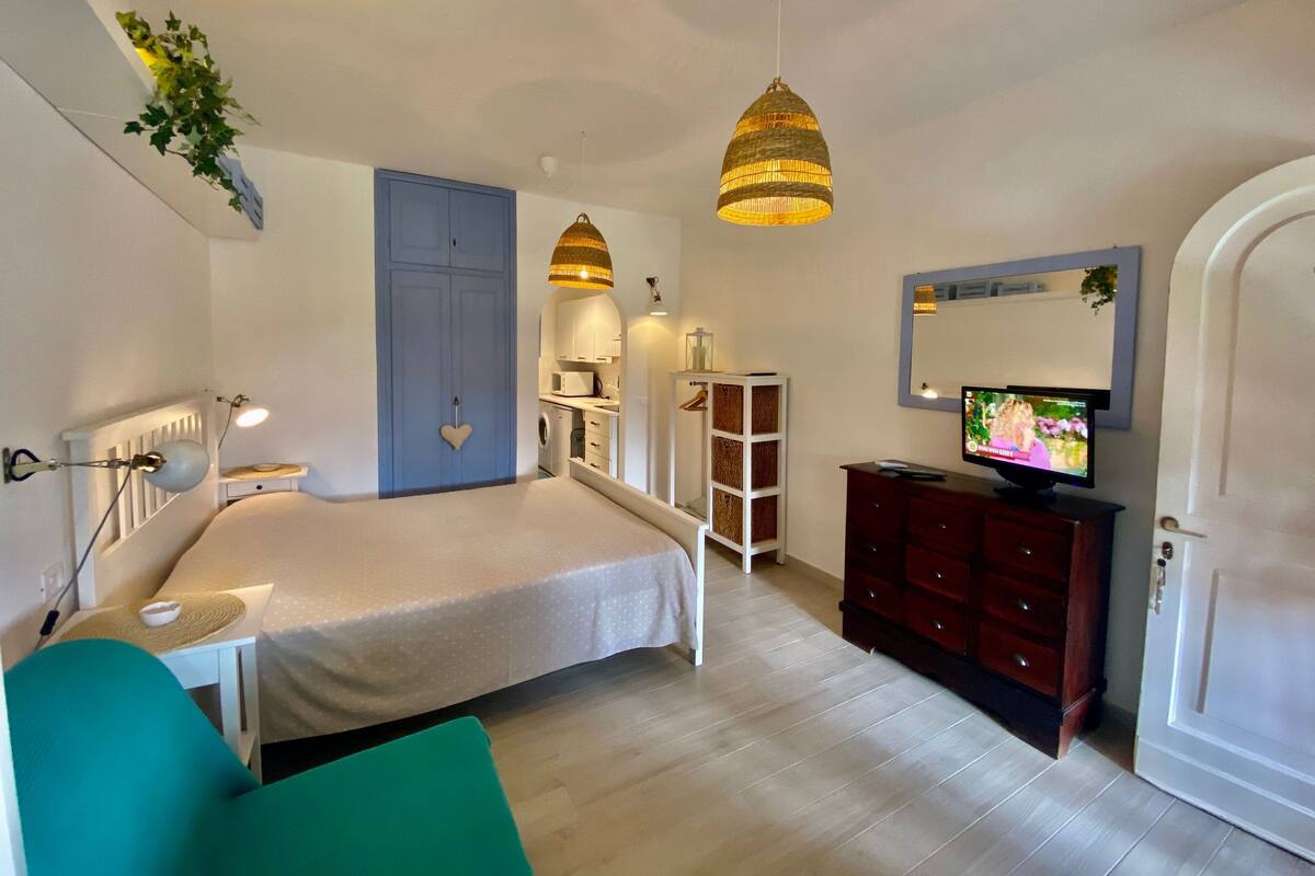 Um quarto com uma cama, cômoda, televisão e guarda-roupa.