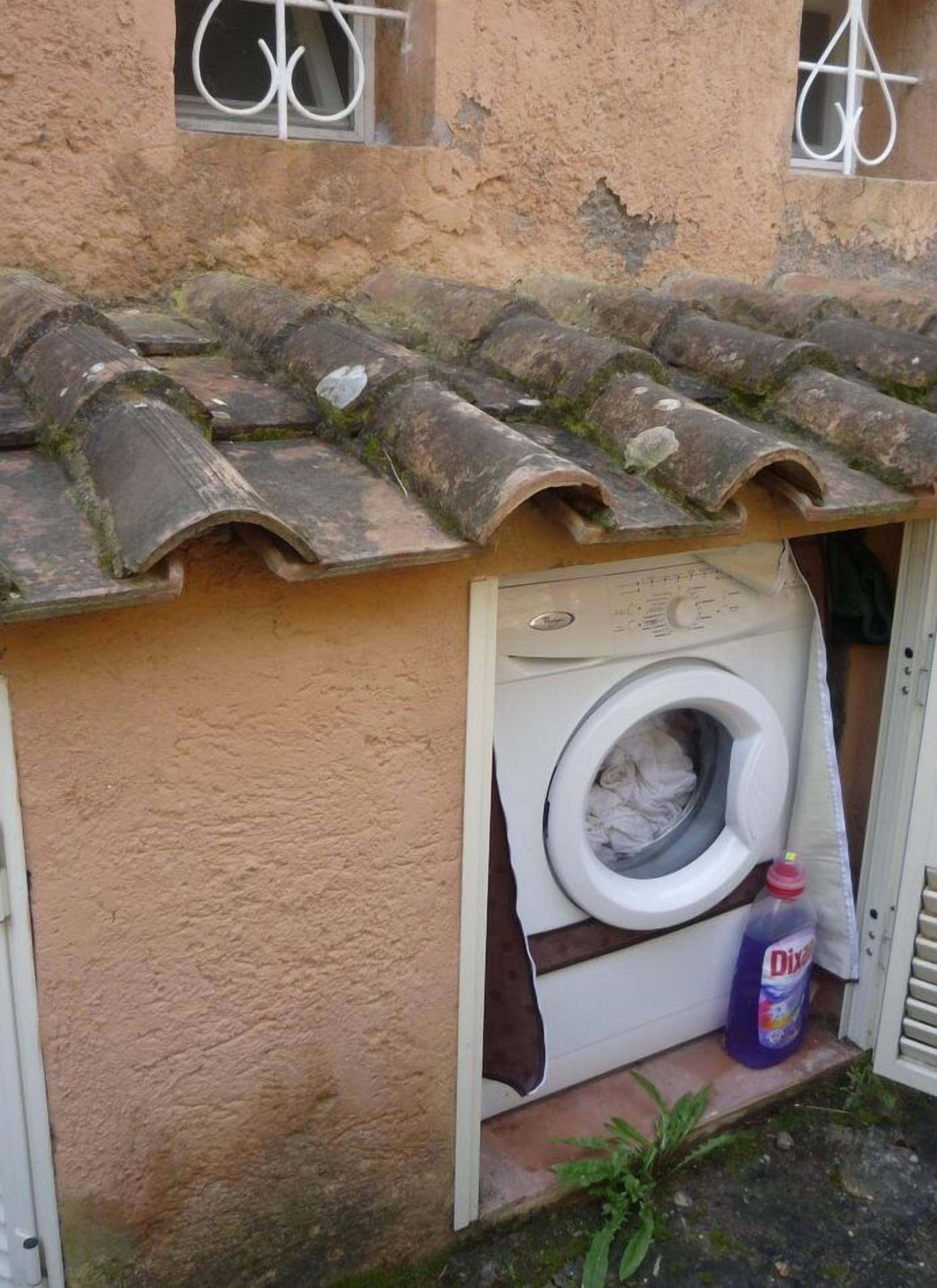 Un piccolo spazio lavanderia con una lavatrice e una bottiglia di detersivo.