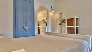 A bedroom with a large bed, a blue door, a wardrobe, and a hanging light fixture. - Il Portolano (Porto Azzurro)