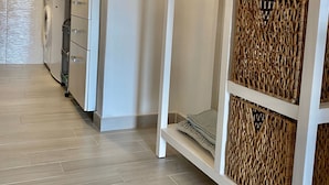 A modern kitchen with white cabinetry, a built-in washing machine, and a hanging rack. - Il Portolano (Porto Azzurro)