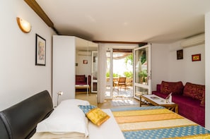 A bedroom with a bed, a sofa, and a dining area. - Apartments Kiki (Dubrovnik)