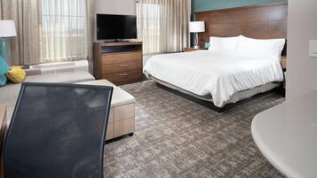 A hotel room with a bed, a desk, a chair, a television, and a bathroom.